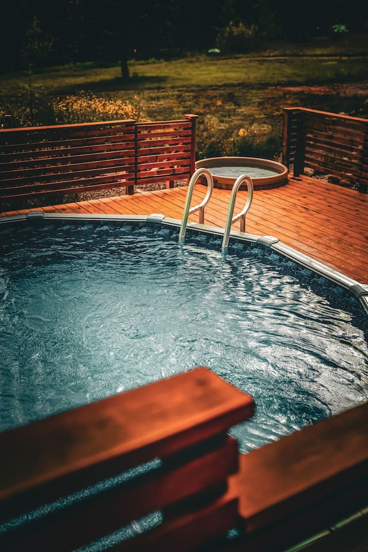 Cedar hot tub and above-ground pool on tiered deck